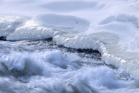 Ice formation formed by frost and freezing cold temperatures over running water of stream along