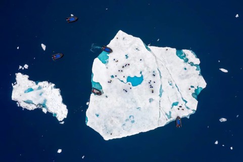 Aerial view over ecotourists from Iceland Pro Cruises walking on ice floe drifting in the Arctic