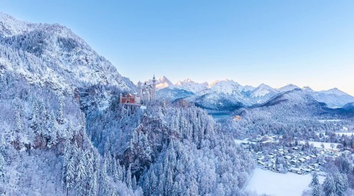 The picturesque Neuschwanstein Castle in winter surrounded by snow-capped mountains and forests at