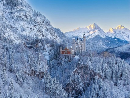 The magnificent Neuschwanstein Castle, surrounded by mountains and glowing snow in the morning