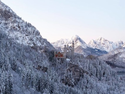 Magnificent Neuschwanstein Castle in the midst of a snowy mountain landscape with majestic peaks,