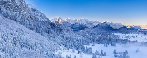 Wide snowy mountain landscape with clear skies and a wide view of the Alps, Neuschwanstein Castle,