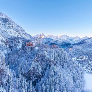 Neuschwanstein Castle rises above a snowy mountain landscape, wrapped in the cold of winter