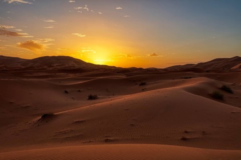 Gently curved sand dunes in the light of a colorful sunset, Sahara in Morocco