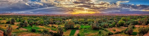 Wide green oasis landscape under a dramatic sunset sky with clouds, Tinghir in Morocco