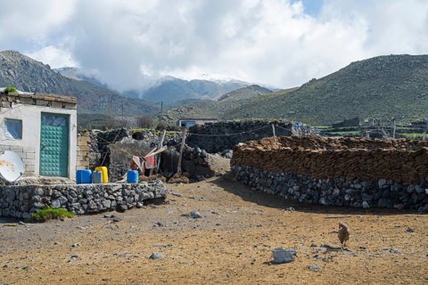 A simple stone building with mountains in the background, village at the foot of Great Ararat with