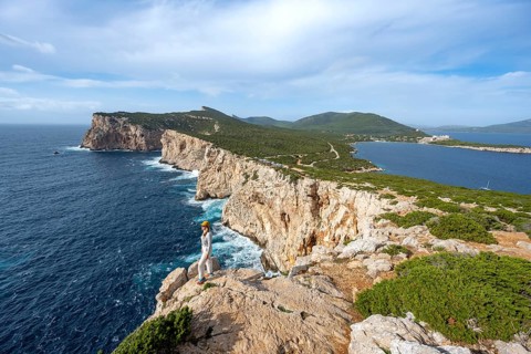Tourist enjoying the view of steep cliffs by the sea, coastal landscape, cliffs on the Capo Caccia