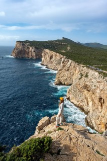 Tourist enjoying the view of steep cliffs by the sea, coastal landscape, cliffs on the Capo Caccia