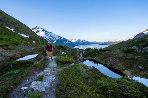 Hikers on Portage Pass, snow-covered mountains and Fjord Passage Canal, near Whittier, Alaska, USA