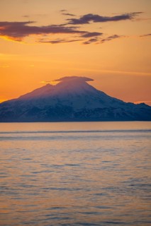 View of Cook Inlet on white mountain peaks of Mount Redoubt at sunset, picturesque golden light of