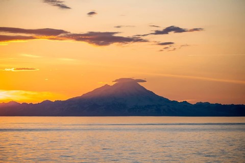 View of Cook Inlet on white mountain peaks of Mount Redoubt at sunset, picturesque golden light of