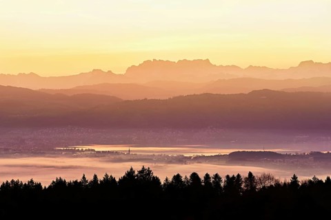 View from Horben of Lake Zug with the city of Cham and Zug covered in fog, behind it the