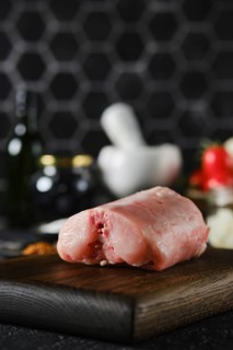 Close-up view of a piece of raw rabbit meat on a wooden cutting board in a contemporary kitchen.