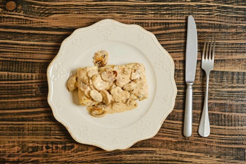 Crepes filled with seasoned meat, topped with a rich and creamy mushroom sauce. The dish is