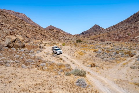 Toyota Hilux off-road vehicle on a sandy track, desert landscape with Brandberg, Erongo,
