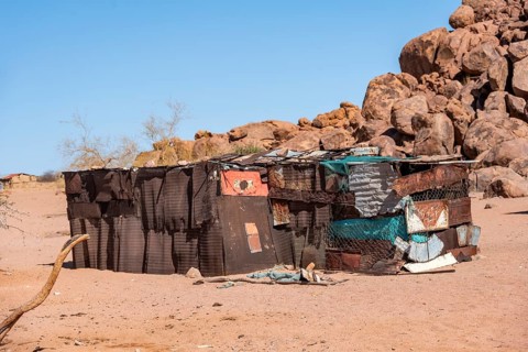 Simple poor huts made of corrugated iron and wood, desert landscape, barren landscape with hills of