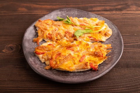 Baked chicken meat with cheese and tomatoes on brown wooden background. side view, close up