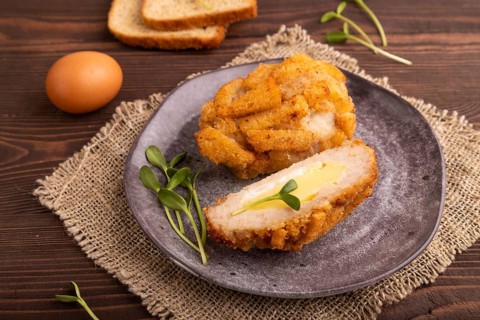 Chicken Schnitzel on gray plate with microgreen on brown wooden background and linen textile. side