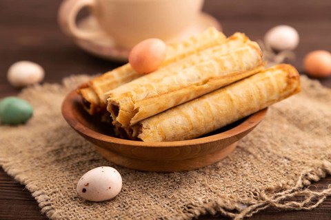 Waffles with caramel on brown wooden background and linen textile, cup of coffee, side view,