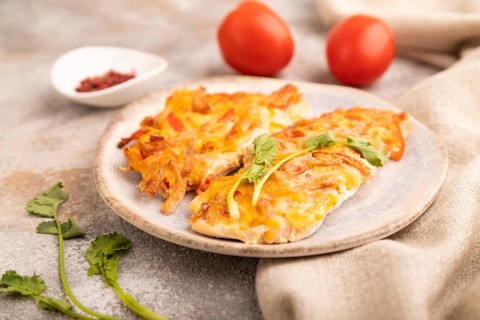 Baked chicken meat with cheese and tomatoes on brown concrete background and linen textile. side