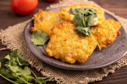 Fried crispy Chicken pancakes on brown wooden background and linen textile. side view, close up,