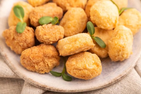 Fried crispy Chicken Nuggets with ketchup, microgreen on brown concrete background and linen