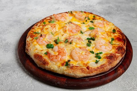 Four cheese pizza with shrimp and fresh microgreens, served on a wooden board, homemade, no people