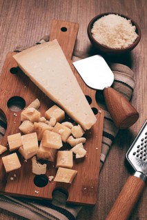 Freshly sliced and grated cheese, parmesan cheese, Gran gusto. Grana padano. on a wooden chopping