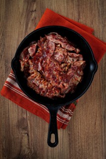 Crispy bacon, on a cast-iron skillet, on a wooden table, rustic style, no people