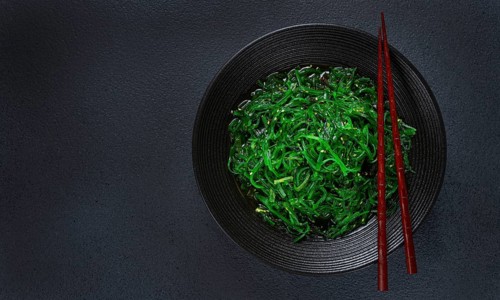 Chuka salad, made from fresh seaweed, with sesame dressing, served in a black bowl, with chopsticks
