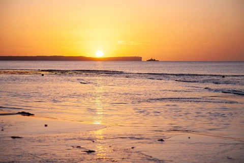 Sunrise over Jervis Bay — View of Point Perpendicular lighthouse. A ship on the horizon