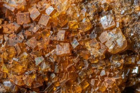 Bright, square crystals are visible on a piece of rock. The light underlines their structure and