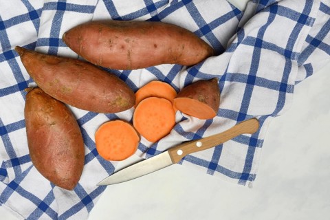 Sweet potatoes with kitchen knife on kitchen towel, Ipomoea batatas