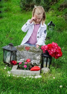 Grieving blonde 7-year-old girl at her cat's grave at pet cemetery in Ystad, Skåne County, Sweden,