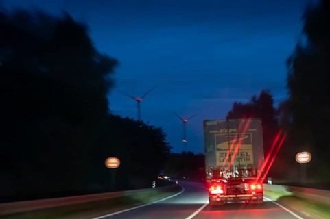 Truck on federal highway at night, wind turbine lights on the left, Schleswig-Holstein, Germany
