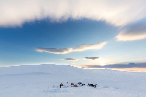 Snowmobiles, snow scooters at Arctic expedition camp with tents protected by tripwire fence against