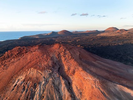 Picturesque volcanic landscape in evening light, red volcano Montaña Bermeja between lava fields,