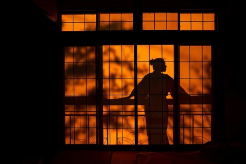 Shadows of a woman in kimono, on the balcony behind sliding shoji doors in a traditional Japanese