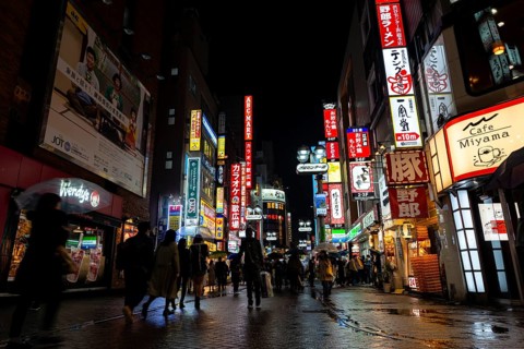 Busy pedestrian zone with many shopping centers and stores, illuminated with lots of neon signs at