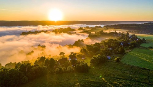 Sunrise over a fog covered village in a rural landscape, golden morning light, serene autumn