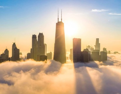 City scape emerging from a dense enveloping fog in sunrise and skyscrapers piercing the haze, big