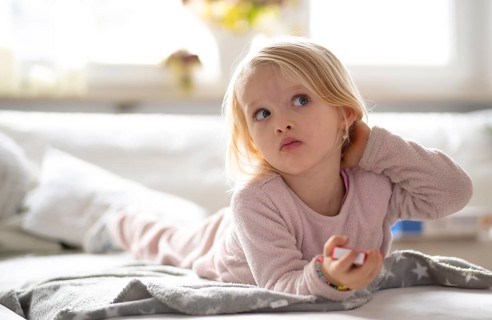 Child, girl, 4 years, blonde, lying on sofa, watching TV, watching television, watching television,