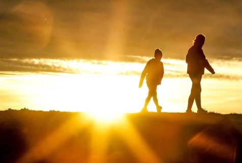 Woman and child walk across a dike on the island of Fehmarn at sunset, 13.10.2025, Fehmarn,