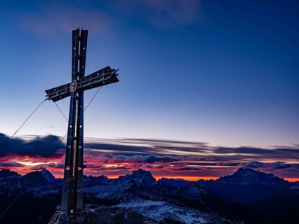 Sassongher summit cross at dawn, in the background Monte Cristallo, Monte Pelmo and Civatta,