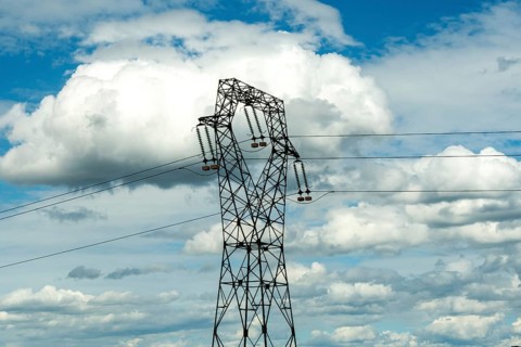 High voltage power lines against a bright blue sky with scattered clouds, Puy de Dome, Auvergne