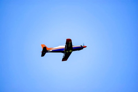 An RC model of a Pilatus PC-21 with advertising for the Swiss watch brand Breitling during a flight