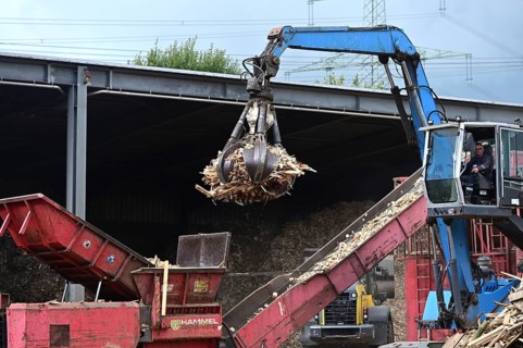 Loading crane with grab arm for loading wood waste for wood pellet production on the premises of
