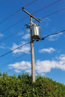 Electricity transformer, high voltage transmission wires, internet, telephone cables attached to