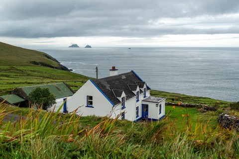 View over green meadows and a white cottage to the Atlantic Ocean and the Skellig Islands, Bolus
