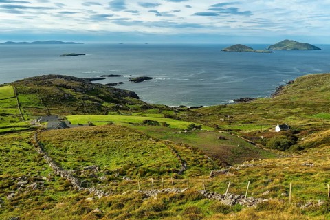 Elevated view over green meadows bordered by natural stone walls and typical cottages to the